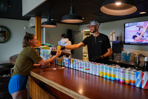Bartender handing canned drink to customer at bar